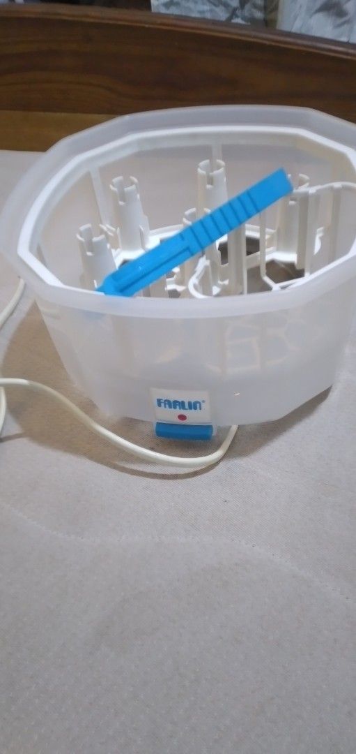 Farlin electric bottle sterilizer and dryer (Category: Breastfeeding & Bottle Feeding) located in Quezon City. Submitted by roxasjr86 (Listing ID 1470195711, Image 1). Description: - Brand: Farlin - Type: Electric bottle sterilizer - Color: Translucent white with blue tongs included - Features: Removable cover, internal bottle rack, and multiple prongs to hold bottles upright - Controls: Easy-access power switch button on the front with attached 