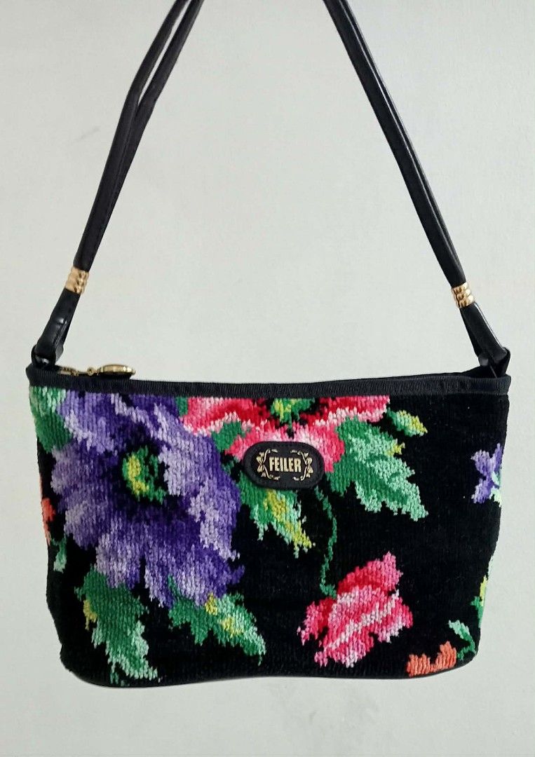 FEILER Chenille Floral Shoulder Bag (Category: Shoulder Bags) located in Siniloan. Submitted by treyyasonlineshop (Listing ID 1470152829, Image 1). Description: - Material: Soft black chenille fabric with colorful purple, pink, and green floral pattern on both sides - Strap: Black leather-like shoulder strap accented with gold-tone hardware links - Closure: Secure zip-top closure - Interior: Fabric-lined with an official brand patch - Fit: Compac