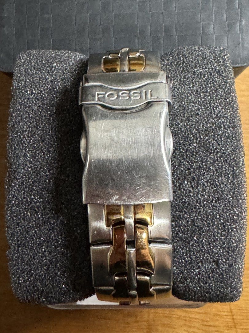 Fossil Two-Tone Chronograph Watch with Tin Box (Category: Men's Watches) located in Valenzuela. Submitted by wisetree_18aeb6 (Listing ID 1470219014, Image 3). Description: - Brand: Fossil - Design: Two-tone silver and gold chronograph watch - Features: Sub-dials for day, date, and 24-hour time, plus a rotating bezel with numeric markers - Material: Durable stainless steel with engraved Fossil clasp closure - Condition: Moderate wear on the metal 