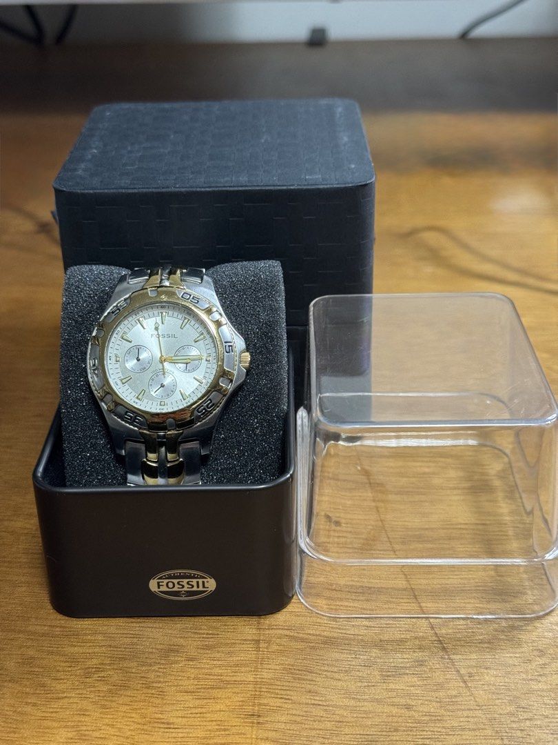 Fossil Two-Tone Chronograph Watch with Tin Box (Category: Men's Watches) located in Valenzuela. Submitted by wisetree_18aeb6 (Listing ID 1470219014, Image 1). Description: - Brand: Fossil - Design: Two-tone silver and gold chronograph watch - Features: Sub-dials for day, date, and 24-hour time, plus a rotating bezel with numeric markers - Material: Durable stainless steel with engraved Fossil clasp closure - Condition: Moderate wear on the metal 