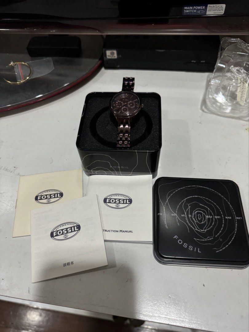 Fossil Women's Multi-Function Watch with Tin Box (Category: Women's Watches) located in Valenzuela. Submitted by wisetree_18aeb6 (Listing ID 1470192427, Image 1). Description: - Authentic Fossil multi-function watch - Dark purple-brown stainless steel link bracelet with deployment clasp - Matching dark dial featuring elegant rose gold markers and hands - Three functional sub-dials displaying day and date - Complete set: Includes original black me