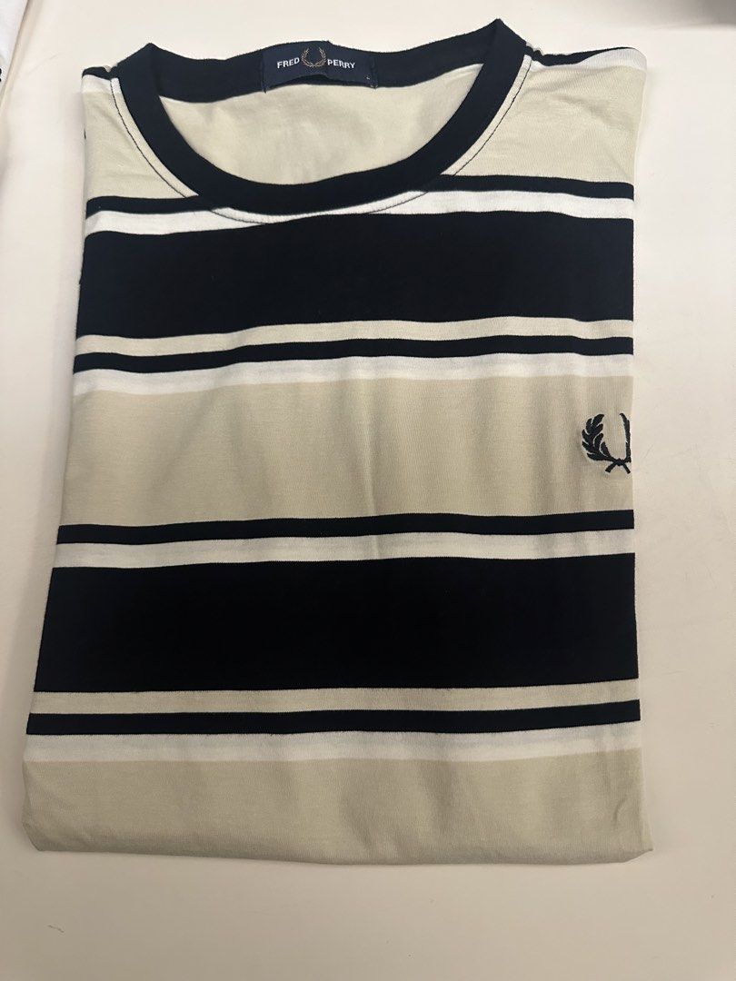 Fred Perry Striped T-Shirt Size L (Category: Tshirts & Polo Shirts ) located in Quezon City. Submitted by adc2011 (Listing ID 1470229101, Image 2). Description: - Brand: Fred Perry - Design: Bold black, white, and beige horizontal stripes - Logo: Classic embroidered laurel wreath on left chest - Material: Soft cotton fabric with ribbed collar and sleeve cuffs - Size: L (inner collar tag) - Condition: Clean, excellent, and ready to wear.