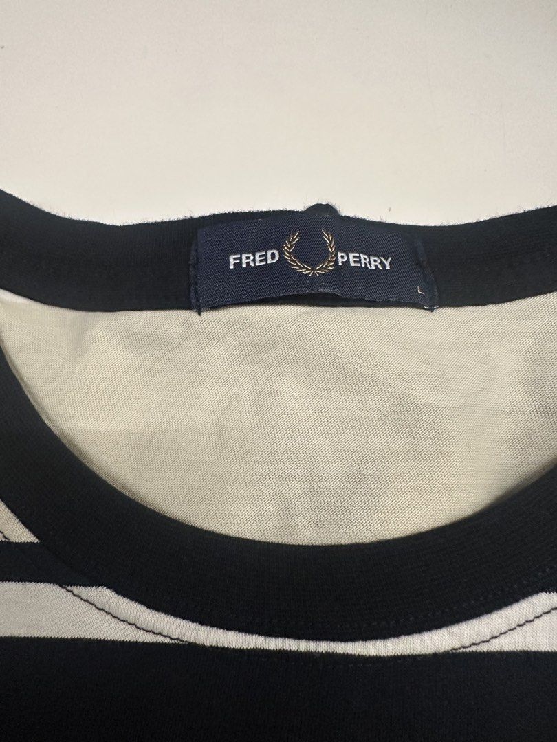 Fred Perry Striped T-Shirt Size L (Category: Tshirts & Polo Shirts ) located in Quezon City. Submitted by adc2011 (Listing ID 1470229101, Image 3). Description: - Brand: Fred Perry - Design: Bold black, white, and beige horizontal stripes - Logo: Classic embroidered laurel wreath on left chest - Material: Soft cotton fabric with ribbed collar and sleeve cuffs - Size: L (inner collar tag) - Condition: Clean, excellent, and ready to wear.