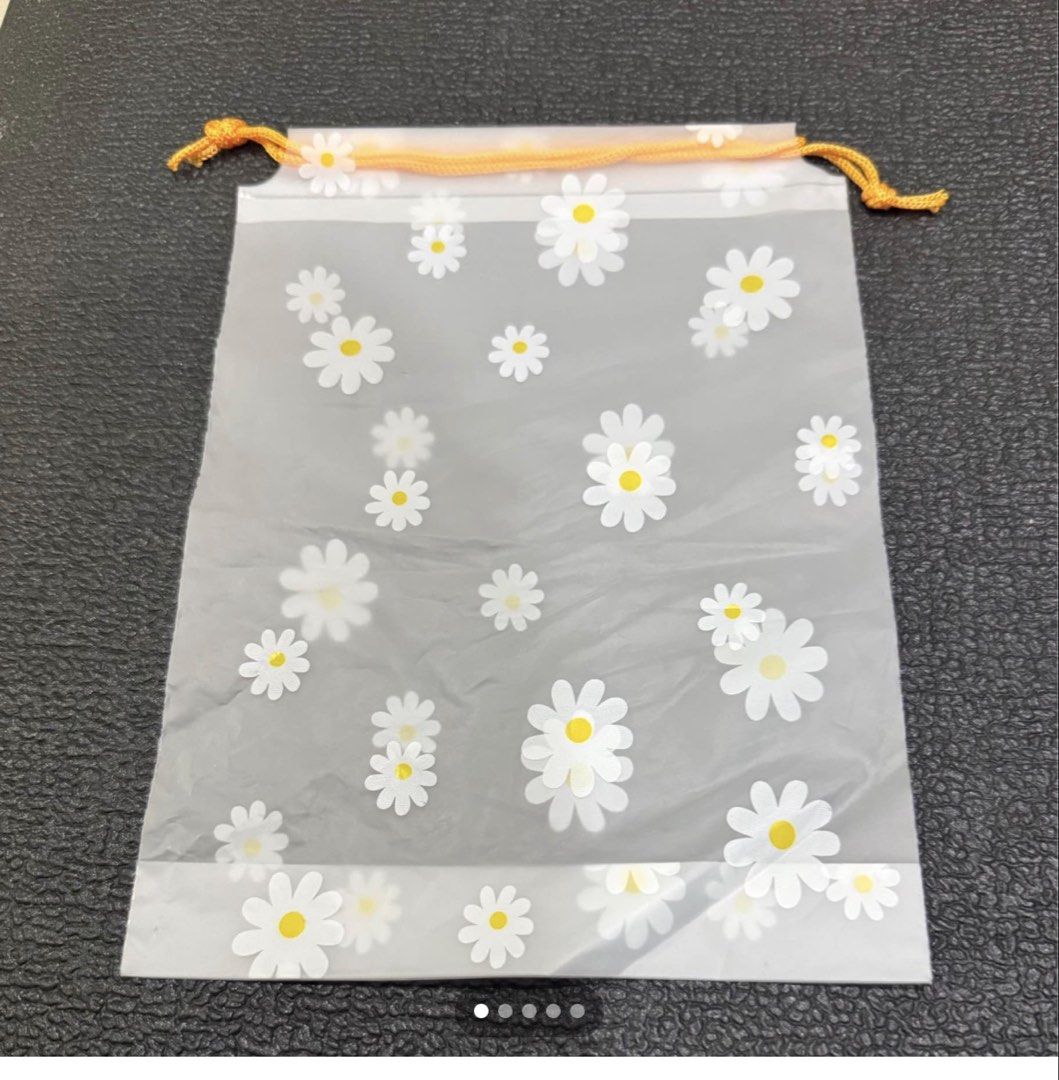 Frosted Daisy Print Drawstring Pouch Bag (100 pieces) (Category: Purses & Pouches) located in Mandaue City. Submitted by erin_grace (Listing ID 1470166796, Image 1). Description: - Design: Frosted translucent pouch with all-over white and yellow daisy print - Closure: Vibrant orange drawstring top - Size: Roughly 9 inches tall x 6.5 inches wide - Uses: Ideal for organizing small items, cosmetics, or as a gift bag - Condition: Brand new and ready 