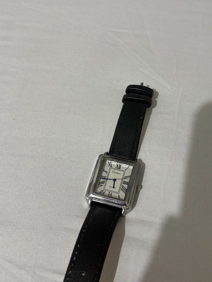 Geduo rectangular quartz watch with black leather strap (Category: Women's Watches) located in Quezon City. Submitted by clareb (Listing ID 1470286004, Image 1). Description: - Brand/Model: Geduo Quartz Dress Watch - Case: Rectangular silver case - Dial: White dial with classic black Roman numerals and striking blue hands - Strap: Black faux leather with beige backing and standard buckle closure - Style: Classic, lightweight, and versatile for ev
