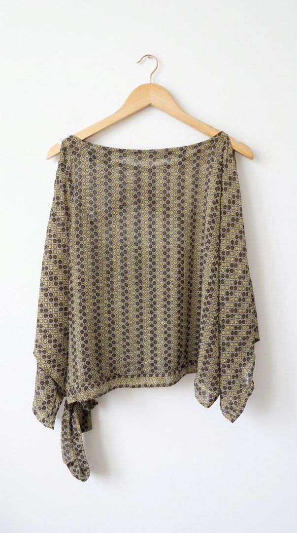 Geometric Pattern Short Sleeve Blouse with Side Tie (Category: Blouses) located in Cavite. Submitted by grandearth.39df3f (Listing ID 1470150655, Image 2). Description: - Design: Brown and yellow geometric print - Fit: Loose, flowy fit with a wide boat neckline and short draped off-the-shoulder sleeves - Detail: Attached side tie with a stylish cascading drape - Fabric: Lightweight and slightly sheer for a breezy feel - Styling: Perfect to pair c