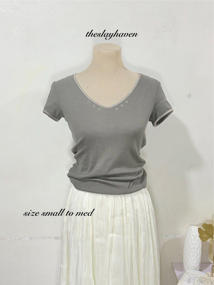 Grey V-Neck Ribbed T-Shirt Small to Medium (Category: Shirts) located in Manila. Submitted by biacakes (Listing ID 1470262409, Image 1). Description: - Color: Grey - Style: Fitted short sleeve top with V-neckline - Details: Metallic eyelets along the collar with contrasting trim - Fabric: Soft, stretchy ribbed material - Size: Fits small to medium comfortably - Condition: Brand new / Excellent - Perfect for effortless everyday casual outfits.