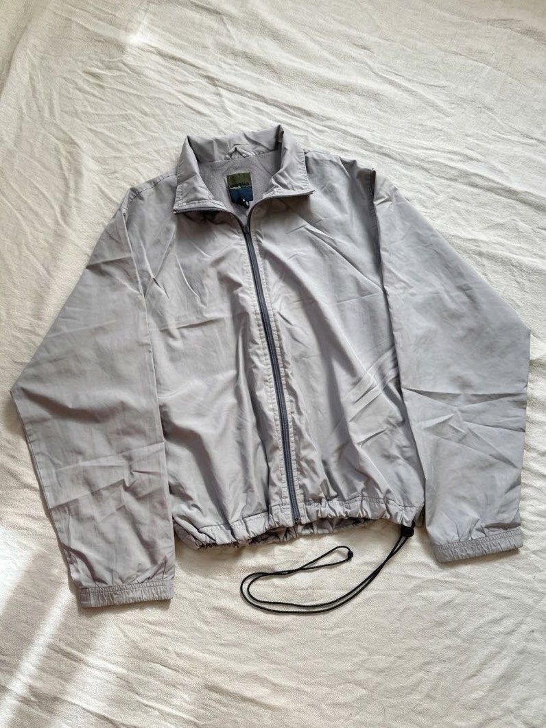 Grey Zip Up Windbreaker Jacket (Category: Coats, Jackets and Outerwear) located in Lipa City. Submitted by collbyisidora (Listing ID 1470308189, Image 1). Description: - Issue: Zipper Pull Tab needs replacement - Color: Light grey - Material: Lightweight, clean fabric - Design: Full front zipper with high collar - Fit: Long sleeves with ribbed cuffs and adjustable drawstring hem - Styling: Easy to throw on over any t-shirt.