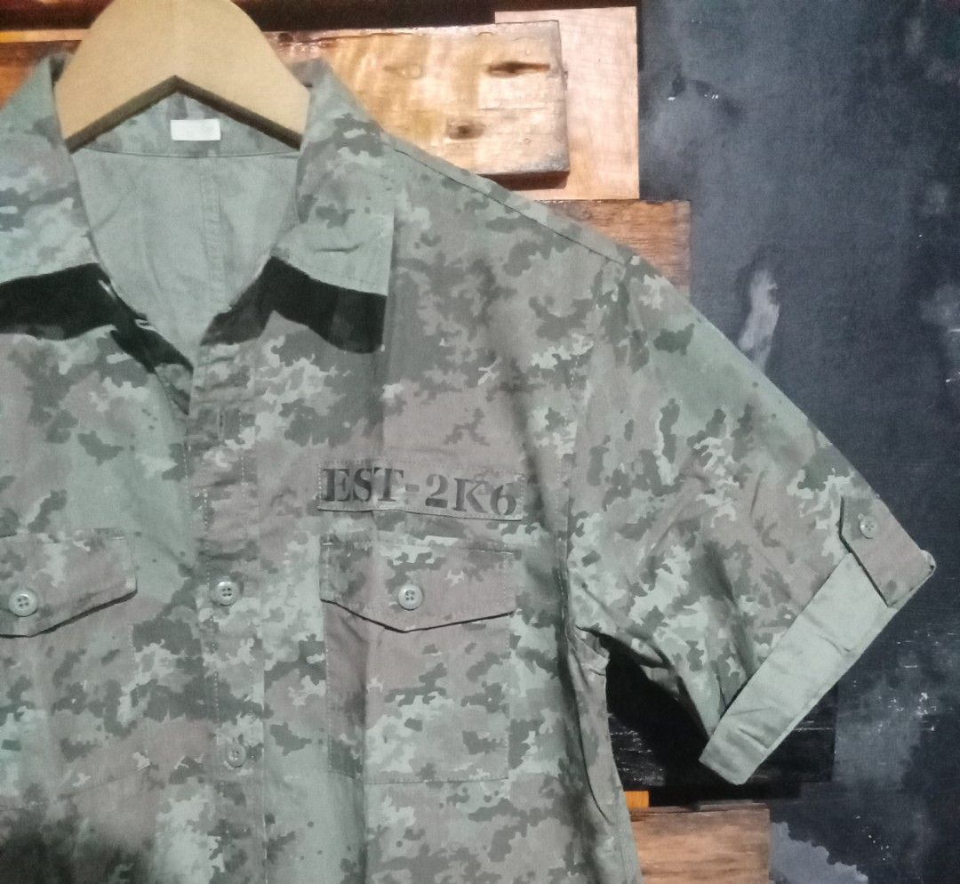 GU Camouflage Short Sleeve Button Up Shirt (Category: Tshirts & Polo Shirts ) located in Caloocan City. Submitted by calmcat_6fd4f7 (Listing ID 1470345357, Image 2). Description: - Brand/Style: GU camouflage short sleeve shirt in green tones - Material: 100% breathable cotton - Size: Tagged M (Width: 20", Length: 27", Arm: 9") - Details: Button-up front, dual chest pockets, and printed text above the left pocket - Condition: Clean, well-maintaine