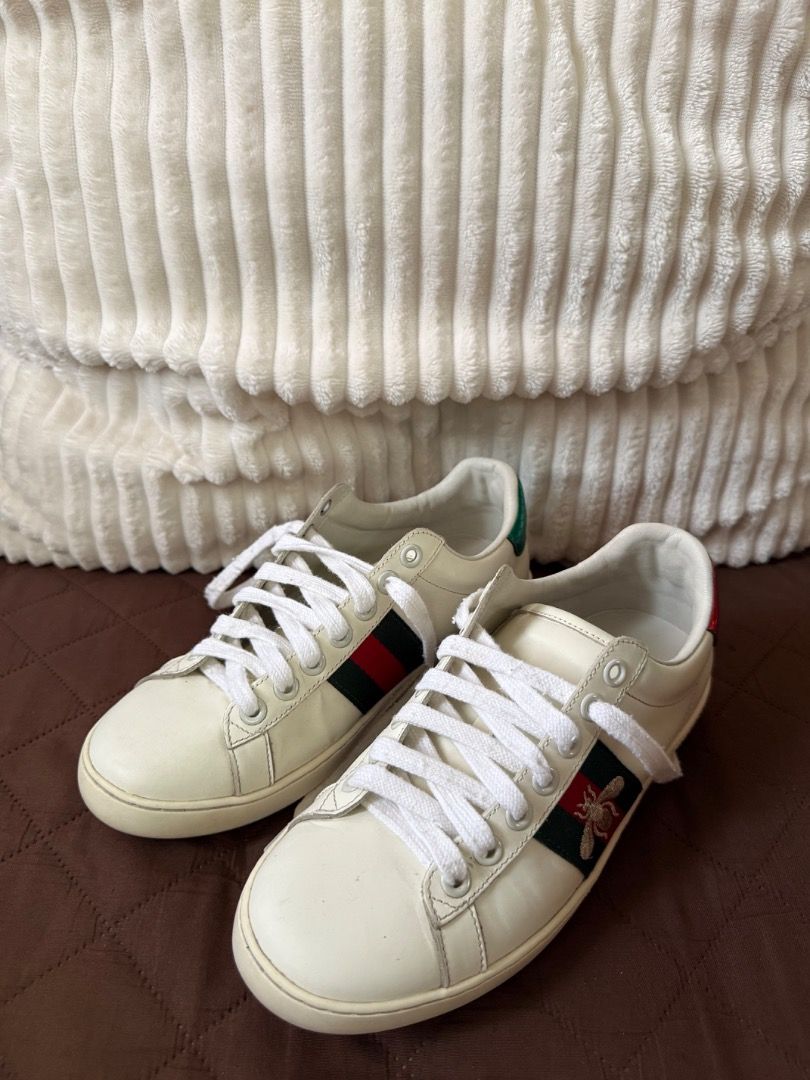 Gucci Ace Bee Sneakers White Leather (Category: Sneakers) located in Caloocan City. Submitted by buritomma (Listing ID 1470158107, Image 1). Description: - Brand: Gucci Ace Low-Top Sneakers - Color: White leather with green and red web stripe - Special Detail: Embroidered gold bee on one shoe, matching green/red heel accents - Condition: Clean overall with minor creasing from light wear - Style: Iconic luxury everyday sneakers.