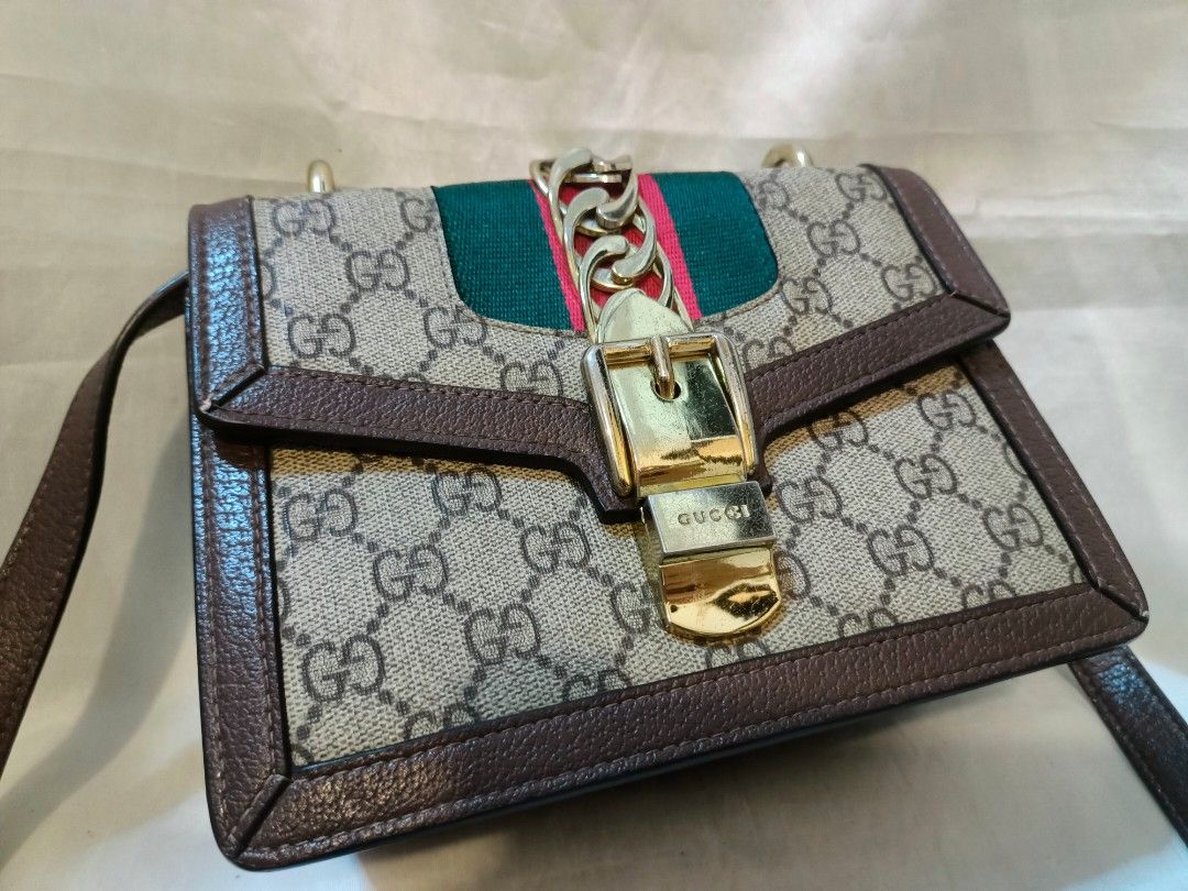 Gucci GG Supreme Sylvie Shoulder Bag (Category: Shoulder Bags) located in Manila. Submitted by minesviewstuffs (Listing ID 1466384172, Image 2). Description: - Gucci Sylvie Shoulder Bag - Material: GG Supreme canvas with premium brown leather trim - Design: Iconic green and red web stripe with gold-tone chain buckle closure - Versatile: Includes a sturdy top handle and an adjustable leather crossbody strap - Shape: Elegant structured rectangular 