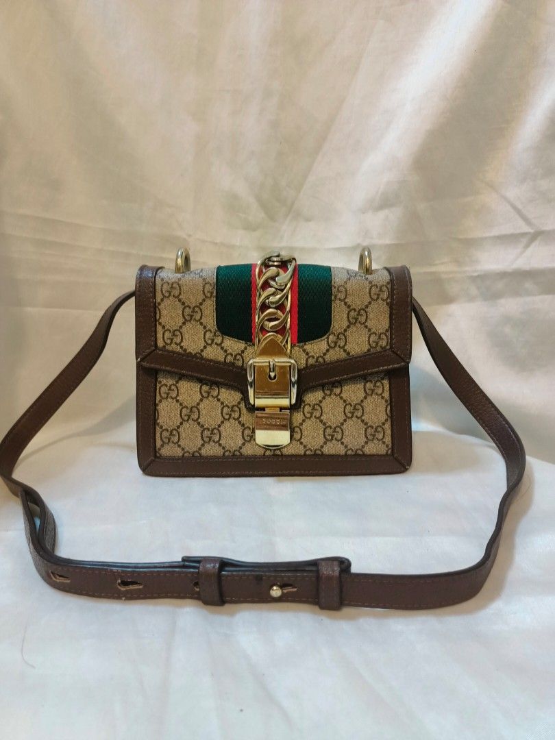 Gucci GG Supreme Sylvie Shoulder Bag (Category: Shoulder Bags) located in Manila. Submitted by minesviewstuffs (Listing ID 1466384172, Image 1). Description: - Gucci Sylvie Shoulder Bag - Material: GG Supreme canvas with premium brown leather trim - Design: Iconic green and red web stripe with gold-tone chain buckle closure - Versatile: Includes a sturdy top handle and an adjustable leather crossbody strap - Shape: Elegant structured rectangular 
