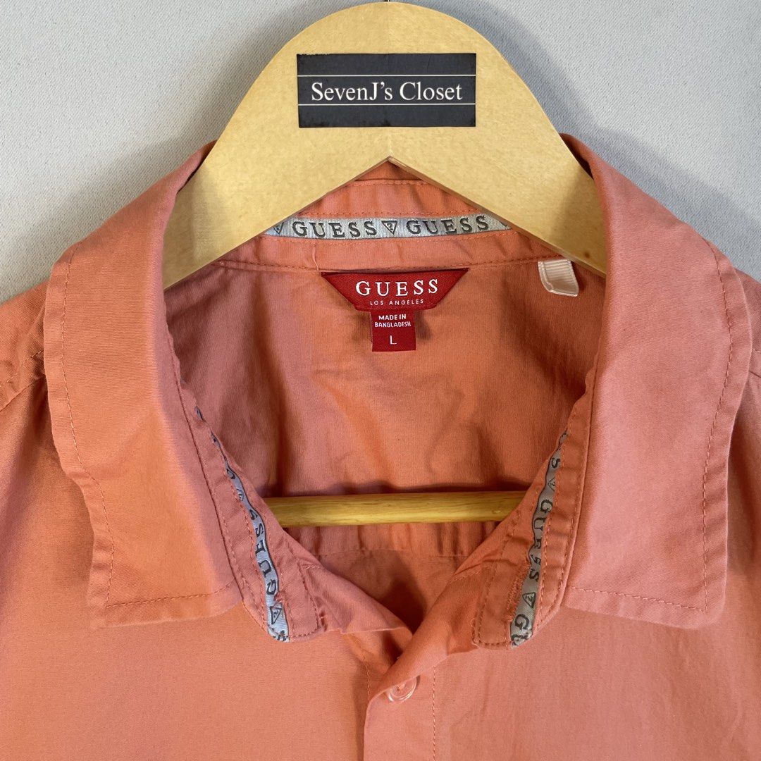 GUESS | Peach Solid Short-Sleeve Button-Down Shirt Size L (Category: Tshirts & Polo Shirts ) located in Norzagaray. Submitted by sevenjscloset (Listing ID 1470273898, Image 2). Description: - Brand: GUESS - Style: Short-sleeve button-down with classic collar - Color: Solid peach - Size: Large on tag - Measurements: 27.5" length x 20.5" width - Fit Reference: Modeled by 5'10" and 70kg individual - Condition: Excellent, no issues or flaws spotted.