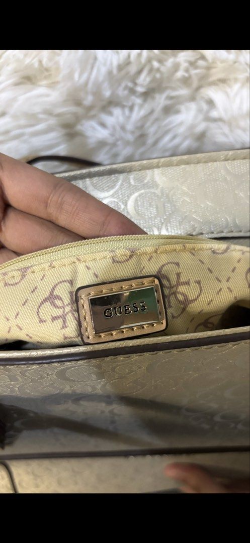 Guess Metallic Gold Monogram Tote Bag (Category: Luxury Bags & Wallets) located in Rizal. Submitted by kianapreloves (Listing ID 1470212396, Image 3). Description: - Brand: Guess - Color: Metallic gold with tan leather-look handles and trim - Pattern: All-over monogram print - Hardware: Metal Guess logo on the front and a stylish hanging logo charm - Closure: Secure zip top closure - Interior: Fabric monogram-patterned lining with an interior pla