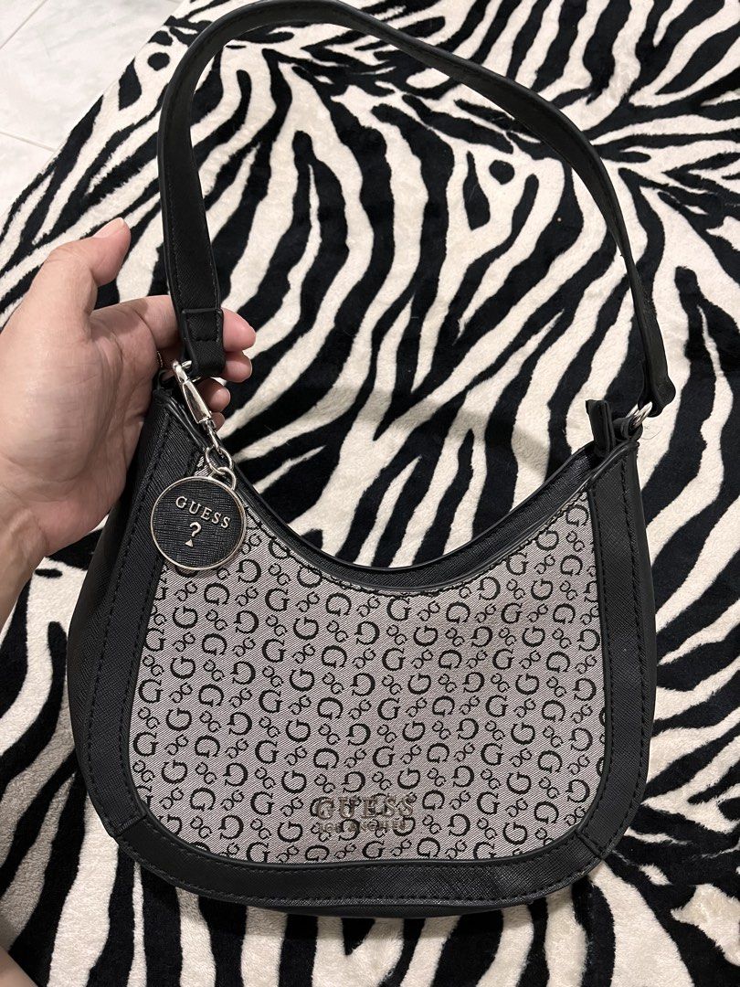 Guess Monogram Black and Grey Shoulder Bag (Category: Shoulder Bags) located in Quezon City. Submitted by pickleballpaddle (Listing ID 1470328822, Image 1). Description: - Brand: Guess - Design: Classic black and grey monogram pattern with faux leather trim - Closure: Secure zip-top closure - Style: Compact curved shape designed to sit comfortably under the arm - Extras: Removable Guess logo charm on the strap base - Interior: Clean lining with a