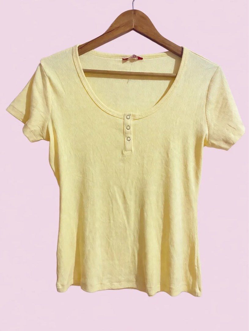 Guess Yellow Ribbed Button Henley Top (Category: Blouses) located in Cavite. Submitted by luxxe.muse (Listing ID 1470289015, Image 1). Description: - Brand: Guess - Color: Trendy pastel butter yellow - Style: Slim fit basic top with scoop neck and short sleeves - Details: 3 decorative front buttons and signature metal Guess logo tag near the hem - Material: Soft, stretchy ribbed cotton for all-day comfort - Condition: Excellent / Like new - Perfe