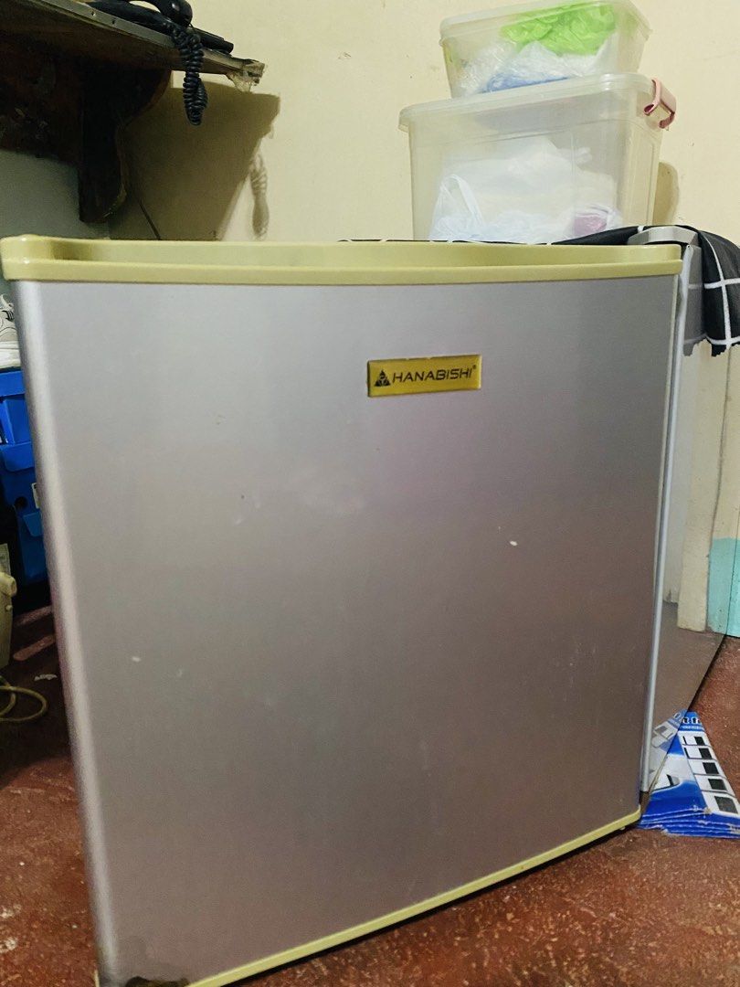 Hanabishi Mini Refrigerator HASREF-18 (Category: Refrigerators and Freezers) located in Makati City. Submitted by a_c_0_7 (Listing ID 1470271059, Image 1). Description: - Brand/Model: Hanabishi HASREF-18 Mini Ref - Color: Silver door body with yellow-toned edges - Design: Single door setup with a top mini freezer compartment - Condition: Powers on normally (220-240V, 60Hz), with visible rust at the bottom base frame - Features: Standard wire setu