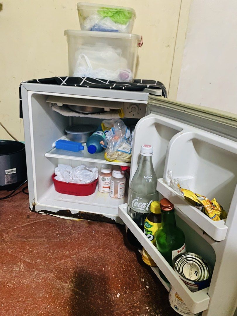 Hanabishi Mini Refrigerator HASREF-18 (Category: Refrigerators and Freezers) located in Makati City. Submitted by a_c_0_7 (Listing ID 1470271059, Image 2). Description: - Brand/Model: Hanabishi HASREF-18 Mini Ref - Color: Silver door body with yellow-toned edges - Design: Single door setup with a top mini freezer compartment - Condition: Powers on normally (220-240V, 60Hz), with visible rust at the bottom base frame - Features: Standard wire setu