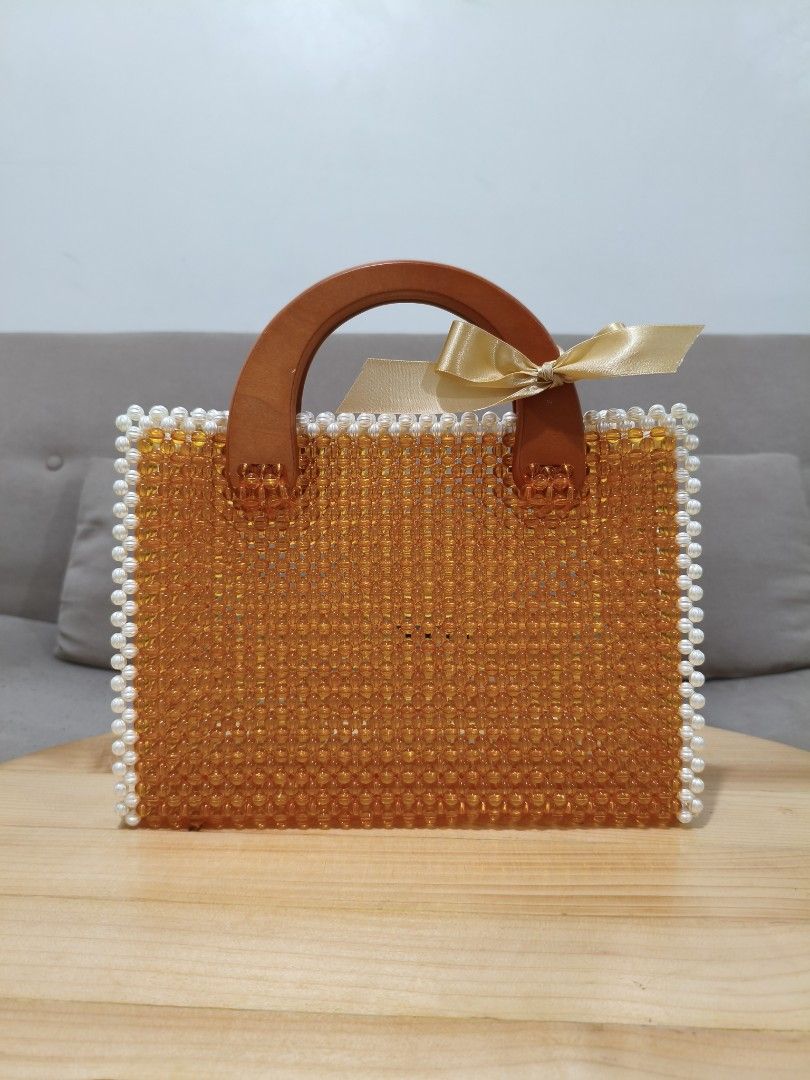 Handmade Amber-Colored Beaded Bag (Category: Shoulder Bags) located in Quezon City. Submitted by petie_ph (Listing ID 1470147181, Image 1). Description: - New, never used - Amber-colored fully beaded handbag with elegant white pearl trim - Features sturdy solid brown wooden top handles - Accented with a charming gold ribbon tied securely on one side - Structured rectangular shape in a handcrafted beaded style - Perfect statement piece for parties