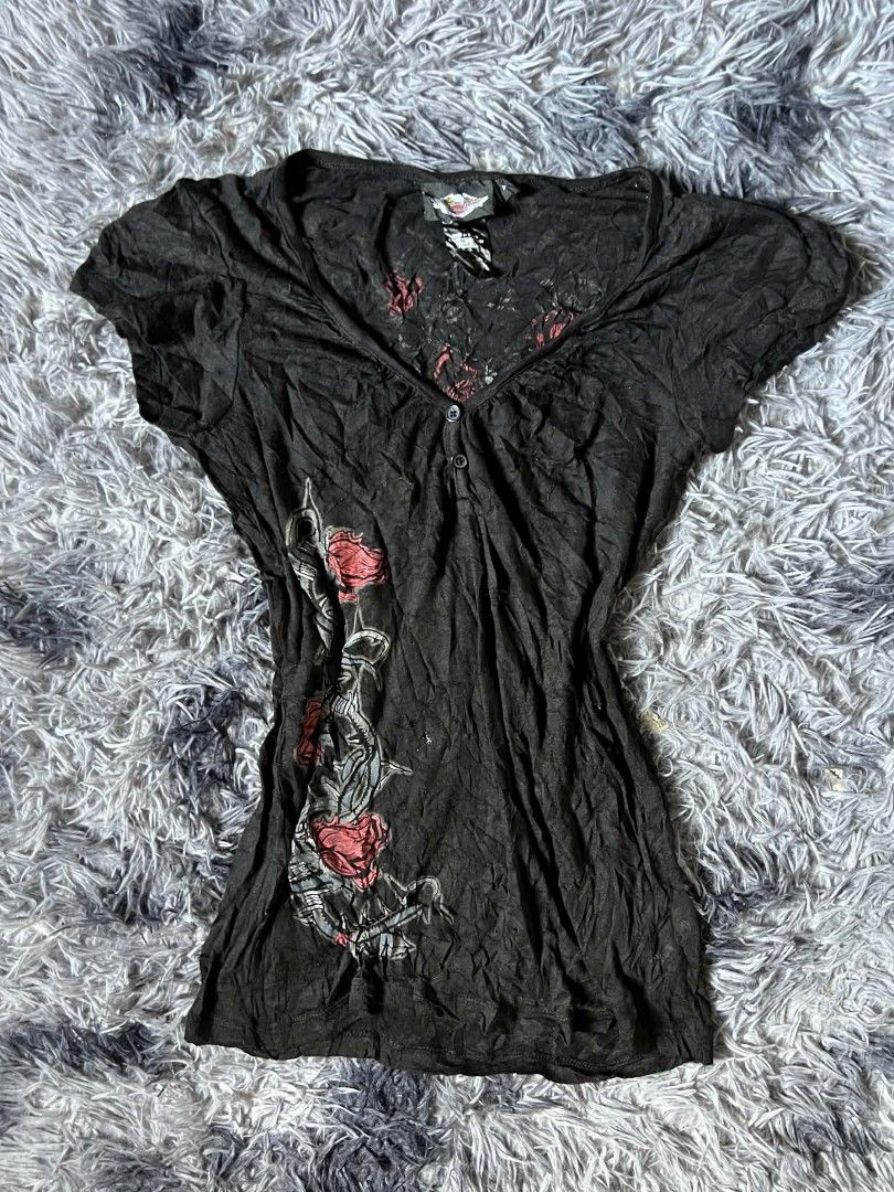 Harley-Davidson Black Rose & Wing Top (Category: Tshirts & Polo Shirts ) located in Tarlac. Submitted by rhandell_collectives (Listing ID 1470194214, Image 1). Description: - Brand: Harley-Davidson - Size: Medium - Color/Fabric: Black with crinkled texture (54% cotton blend) - Neckline: V-neck with two buttons - Sleeves: Short sleeves - Front Design: Red roses and thorny vines graphic on the left side - Back Design: Large signature winged banner 