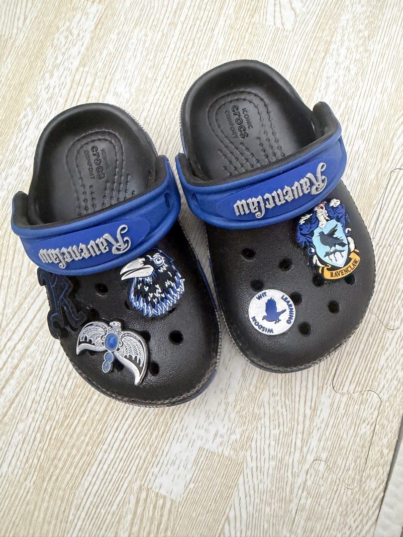 Harry Potter Ravenclaw Crocs Clogs Size C6 (Category: Babies & Kids Fashion) located in Naga. Submitted by suit_yourslf (Listing ID 1470151376, Image 1). Description: - Item: Harry Potter Ravenclaw Crocs Clog Sandals - Size: C6 (indicated on outsole) - Color/Design: Black base with blue heel strap and Ravenclaw lettering - Included Charms: Ravenclaw crest, raven, and house motto badge - Features: Slip-on design and ventilation holes - Condition: 