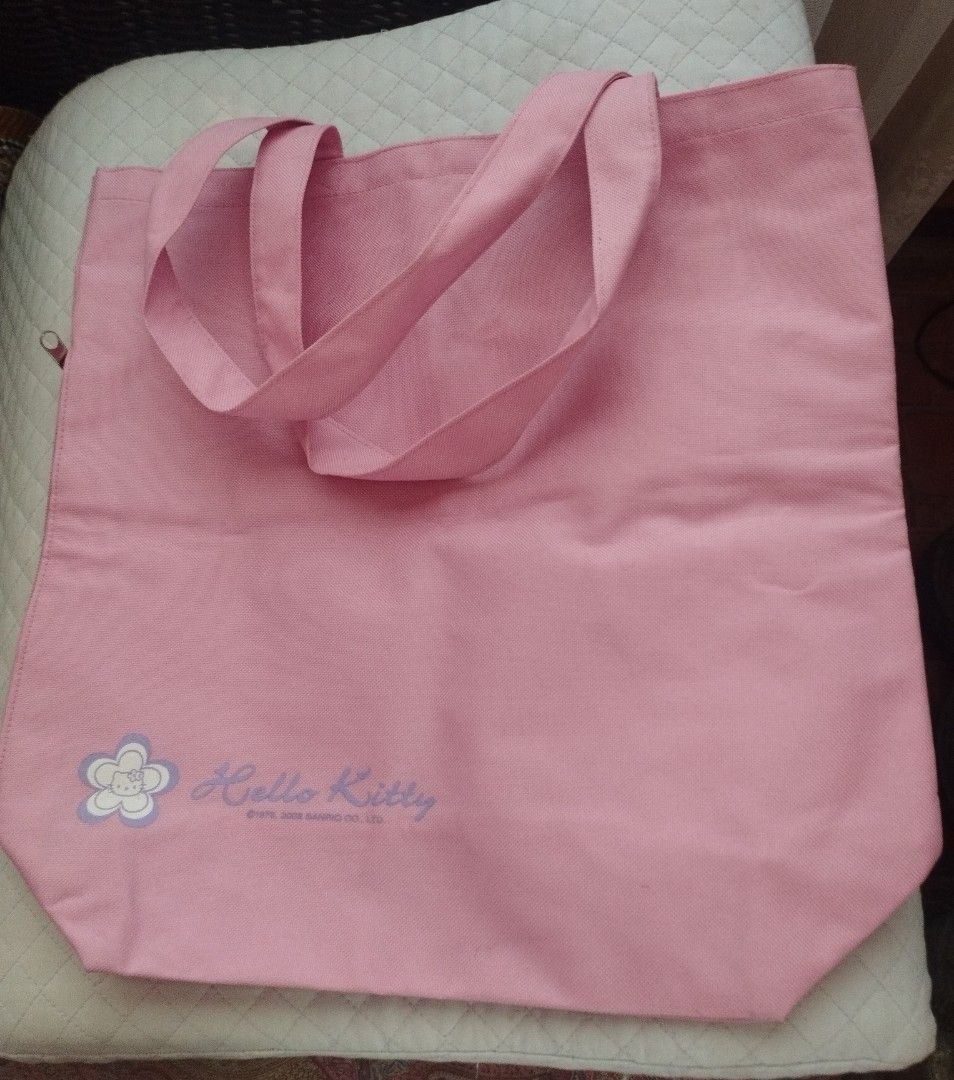 Hello Kitty Pink Canvas Tote Bag (Category: Tote Bags) located in Baguio. Submitted by katgon2016 (Listing ID 1470292500, Image 2). Description: - Pink canvas tote bag featuring Kitty branding and a cute lower front flower graphic - Roomy interior, ideal for school, work, or daily errands - Dual shoulder straps for comfortable everyday wear - Includes a zippered side pocket with an adorable metallic Kitty zipper charm.