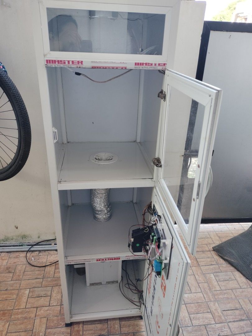 Helmet Vacuum machine (Category: Virtual Reality) located in Bulacan. Submitted by epicriver.0ac812 (Listing ID 1470155258, Image 2). Description: - White aluminum cabinet with glass doors - Lower compartment includes wiring, circuit boards, and digital display - Equipped with internal cooling fa n, ventilation duct, and lighting tubes - Features Master and Honor Home branding stickers - Clean interior with built-in ventilation grilles - Solid co