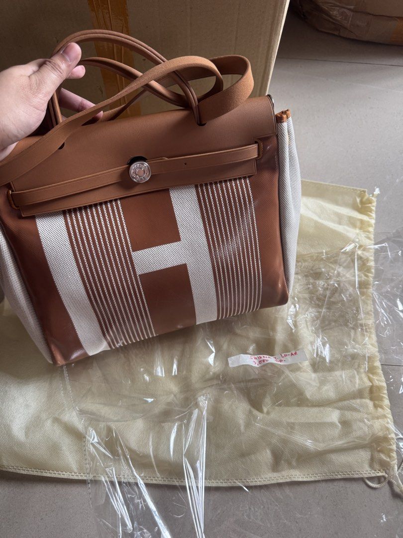 Hermes Brown Canvas and Leather Handbag (Category: Luxury Bags & Wallets) located in Cebu City. Submitted by latendacebu (Listing ID 1470191031, Image 1). Description: - Hermès handbag - Material: Brown and white canvas with premium leather trim - Hardware: Elegant gold-tone accents - Closure: Front flap with secure strap detail - Condition: Minor surface scratches on leather and a small scuff near the zipper pocket; clean interior and holds stru
