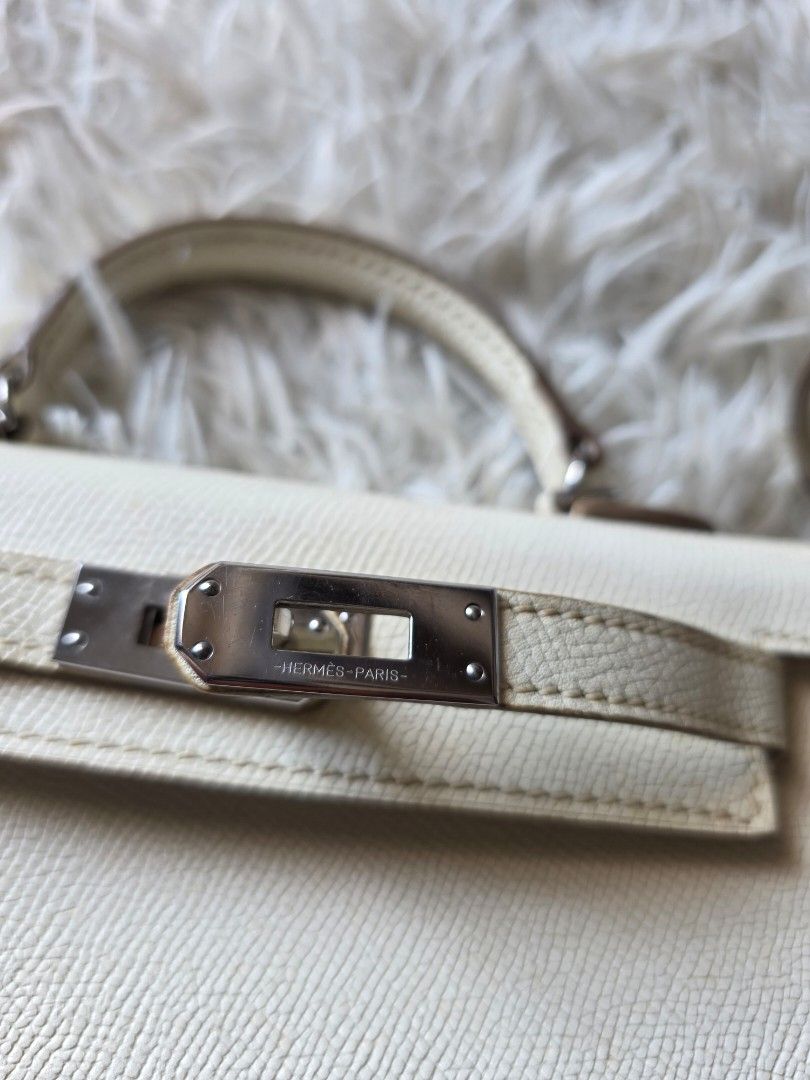 Hermes Paris White Leather Mini Kelly Handbag (Category: Cross-body Bags) located in Lemery. Submitted by venus23 (Listing ID 1470145469, Image 3). Description: - Hermes Paris Mini Kelly handbag - White textured leather with sleek silver-tone hardware and signature clasp closure - Features a sturdy single top handle and a convenient detachable matching shoulder strap - Compact structure (approx. 7 inches across) with protective metal feet on the 