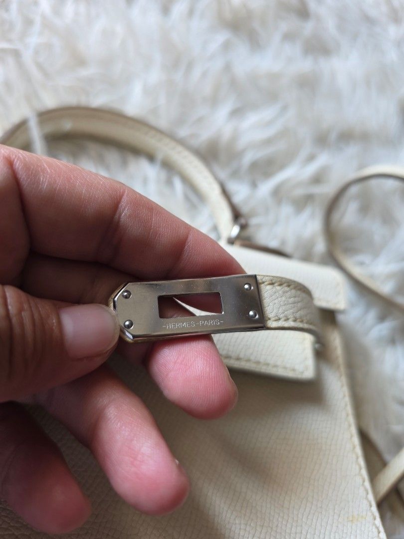 Hermes Paris White Leather Mini Kelly Handbag (Category: Cross-body Bags) located in Lemery. Submitted by venus23 (Listing ID 1470145469, Image 2). Description: - Hermes Paris Mini Kelly handbag - White textured leather with sleek silver-tone hardware and signature clasp closure - Features a sturdy single top handle and a convenient detachable matching shoulder strap - Compact structure (approx. 7 inches across) with protective metal feet on the 