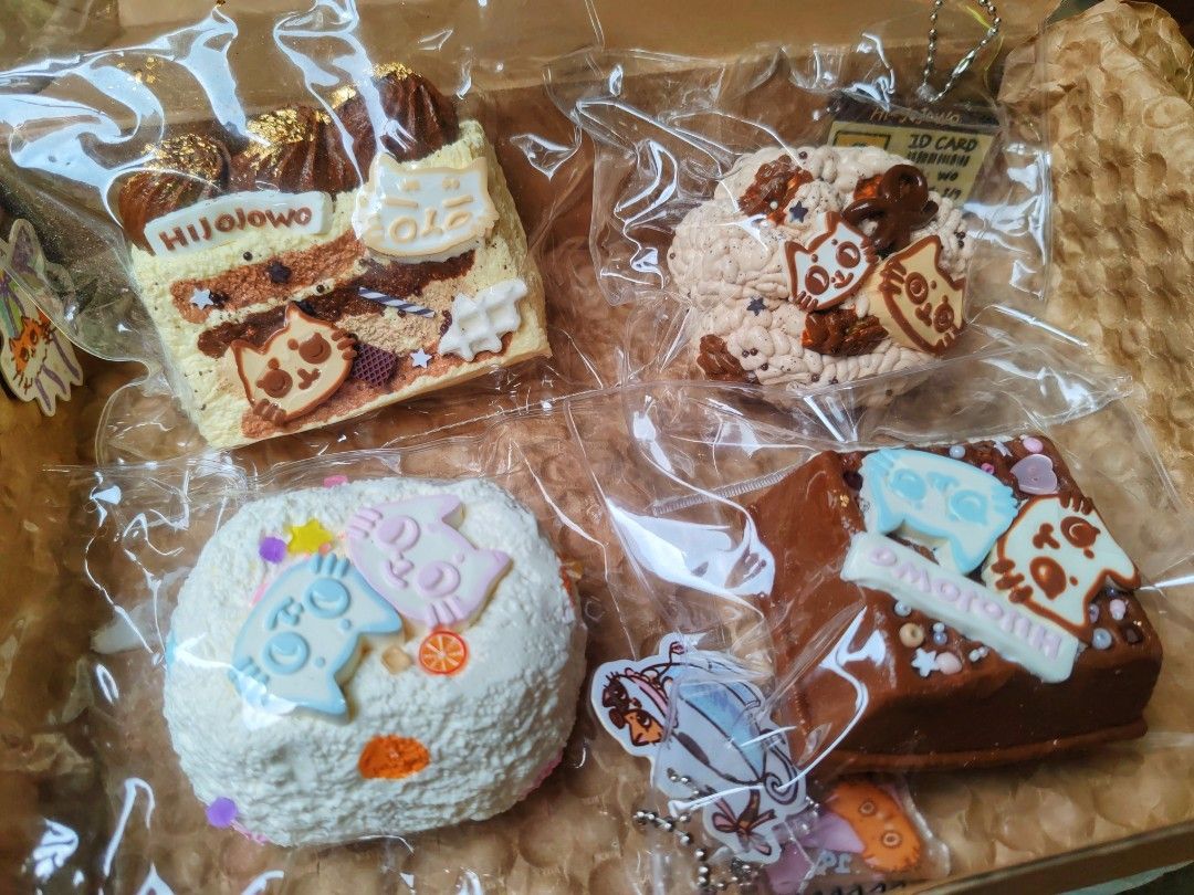Hijiolowo Cat Cake Squishy Toy (Category: Kids Toys) located in Manila. Submitted by icedcoffee_002 (Listing ID 1470317811, Image 1). Description: - Brand new set of 4 Hijiolowo cat-themed cake squishies - Includes: chocolate cake slice, textured brown swirl bun, white frosted mini cake (blue/pink cat faces), and chocolate block cake with light blue cat topper - Made of super soft, slow-rise material - Comes with bonus mini ID cards and extra sti