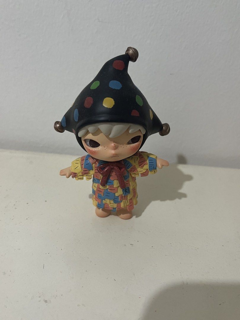 Hirono Jester Figure Pop Mart Blind Box (Category: Designer & Blind Box Toys) located in Pasig City. Submitted by chloe_miel (Listing ID 1470270253, Image 1). Description: - Authentic Pop Mart Hirono Jester collectible figurine - Features detailed white hair, freckles, and signature sullen expression - Wears a black jester hat with colorful polka dots and jingle bells - Multicolored patterned outfit complete with a red collar bow - Stands upright