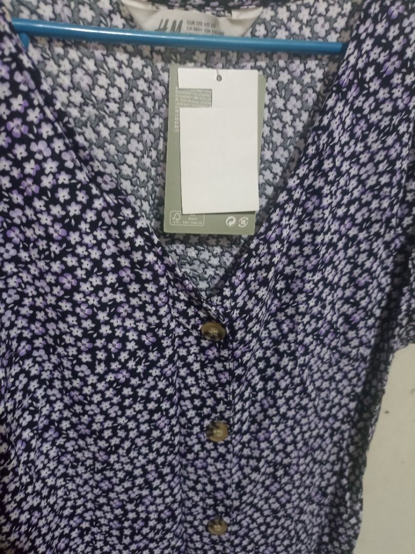 H&M Floral Button-Front Dress (Category: Dresses) located in Binangonan. Submitted by livelion_f56acf (Listing ID 1470144717, Image 3). Description: - Brand: H&M (Brand new with tags still attached) - Color/Design: Dark navy blue with tiny white and purple floral print - Details: Short sleeves, V-neckline, and functional brown front buttons - Material: 100% Lenzing Ecovero viscose (super soft, lightweight, and breathable) - Size: EUR 170 / 14Y+ -