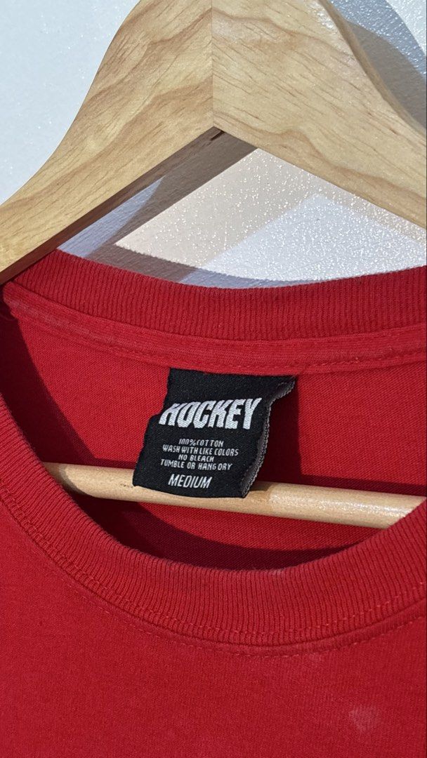 Hockey Skateboards Red Graphic Tee Medium (Category: Tshirts & Polo Shirts ) located in Manila. Submitted by glano (Listing ID 1470298137, Image 3). Description: - Brand: Hockey Skateboards - Color: Red - Size: Medium (Tagged) - Material: 100% Cotton - Design: Bold front graphic of a person in a straightjacket with stylized brand text - Details: Crew neckline, standard short sleeves - Condition: Clean fabric with minimal wear on tags and graphic.
