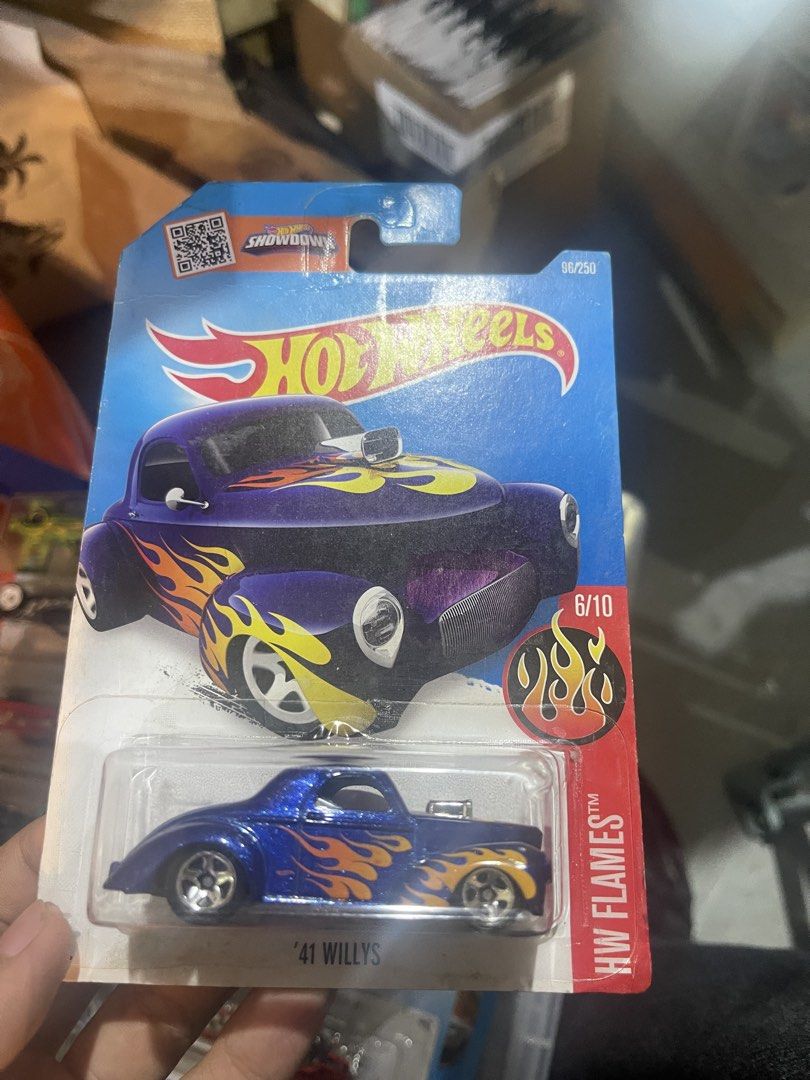 Hot Wheels '41 Willys HW Flames Blue Diecast (Category: Vehicle & Diecast Models) located in Marikina City. Submitted by starlettonabudget (Listing ID 1470251552, Image 1). Description: - Brand: Hot Wheels - Model: '41 Willys (HW Flames Series, 96/250, 6/10) - Color/Design: Deep blue sparkle paint with striking orange and yellow flames - Details: Cool chrome engine sticking out of the hood - Condition: Brand new, unopened packaging with minor she
