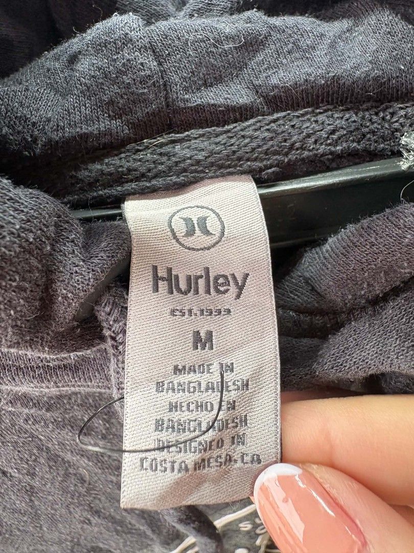 Hurley Surf Co. Black Pullover Hoodie Size M (Category: Hoodies) located in Caloocan City. Submitted by jerksz (Listing ID 1470218588, Image 2). Description: - Brand: Hurley - Color: Black with large white chest graphic - Size: Medium (tag attached) - Material: Comfortable cotton blend, made in Bangladesh - Features: Front kangaroo pocket, adjustable drawstring hood with metal eyelets - Condition: Great for daily casual wear and cooler weather.