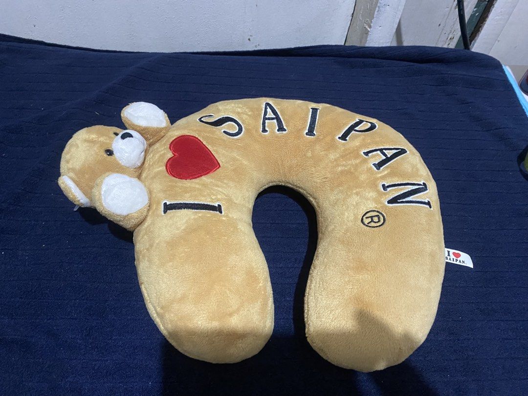 I Love Saipan Teddy Bear Neck Pillow (Category: Bedding & Towels) located in Manila. Submitted by resi.diaz (Listing ID 1470329475, Image 1). Description: - Color: Tan with black and red embroidered 'I (heart) SAIPAN' text - Design: Cute attached teddy bear head and paws hugging the top - Condition: Clean fabric overall, includes official souvenir tag - Material: Super soft plush - Ideal for: Long flights, road trips, or relaxing at home.