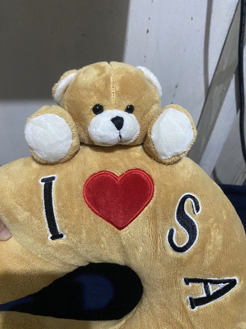 I Love Saipan Teddy Bear Neck Pillow (Category: Bedding & Towels) located in Manila. Submitted by resi.diaz (Listing ID 1470329475, Image 2). Description: - Color: Tan with black and red embroidered 'I (heart) SAIPAN' text - Design: Cute attached teddy bear head and paws hugging the top - Condition: Clean fabric overall, includes official souvenir tag - Material: Super soft plush - Ideal for: Long flights, road trips, or relaxing at home.