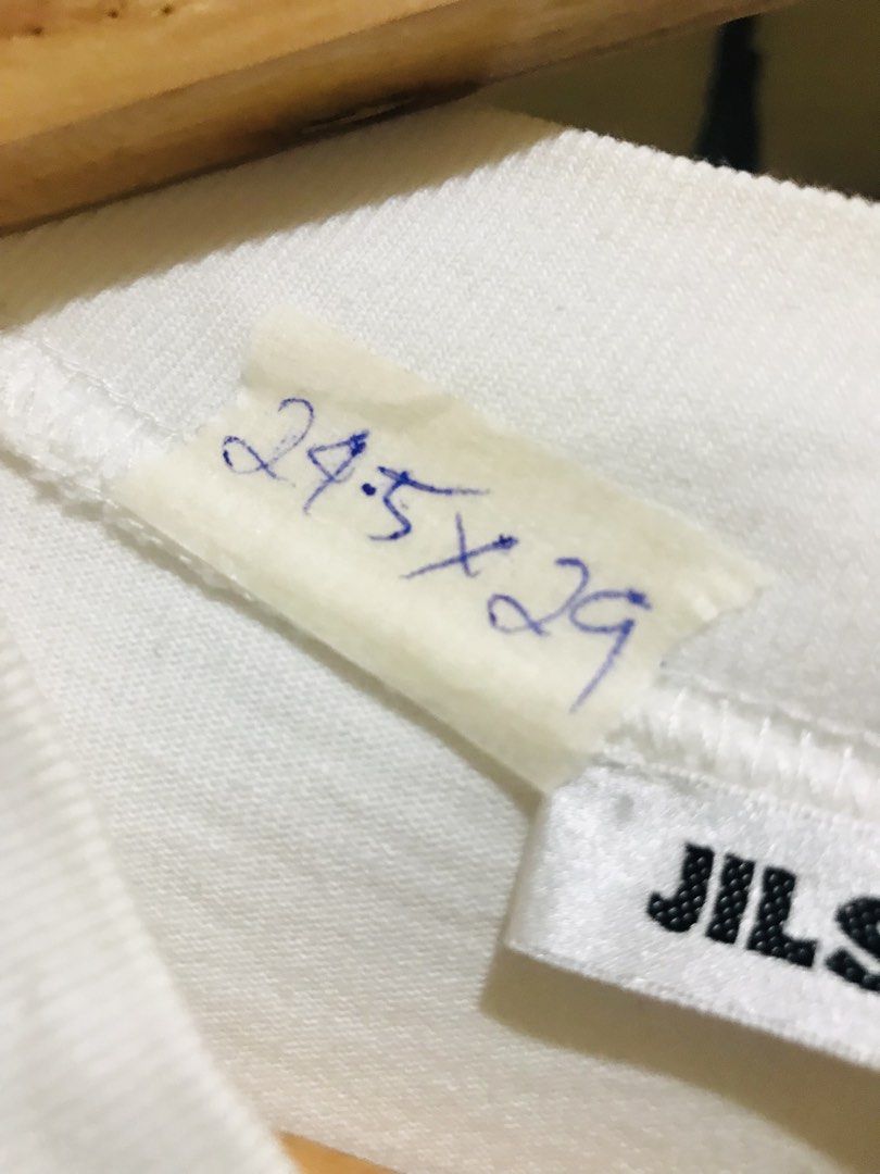Jil Sander White Logo Tee (Category: Luxury Apparel) located in Manila. Submitted by luxurybrandedthrift05 (Listing ID 1470214106, Image 3). Description: - Brand: Jil Sander - Color: White with large black front logo - Material: 100% heavy cotton, made in Italy - Design: Short sleeves, crew neck collar - Condition: Clean fabric, excellent quality - Authenticity: Includes full interior care and product code labels.