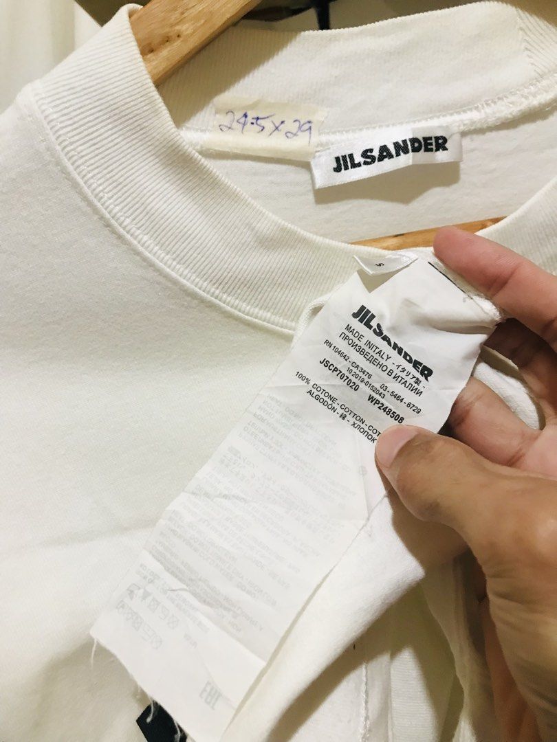 Jil Sander White Logo Tee (Category: Luxury Apparel) located in Manila. Submitted by luxurybrandedthrift05 (Listing ID 1470214106, Image 2). Description: - Brand: Jil Sander - Color: White with large black front logo - Material: 100% heavy cotton, made in Italy - Design: Short sleeves, crew neck collar - Condition: Clean fabric, excellent quality - Authenticity: Includes full interior care and product code labels.