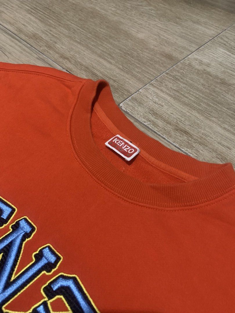 Kenzo Orange Tiger Embroidered Sweatshirt Size M (Category: Luxury Apparel) located in Tarlac. Submitted by luxurious_apparel (Listing ID 1470264373, Image 3). Description: - Brand: Kenzo - Color: Vibrant Orange - Size: Medium (Made in Portugal) - Design: Bold embroidered tiger head graphic with blue lettering - Details: Classic crew neck with ribbed collar, cuffs, and hem - Condition: Clean interior and well-maintained.