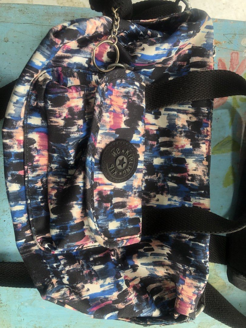 Kipling multi-color abstract print shoulder bag with black straps (Category: Cross-body Bags) located in Cebu City. Submitted by dadulaaile66782 (Listing ID 1470158151, Image 1). Description: - Brand: Kipling shoulder bag - Design: Vibrant multi-color abstract print with black fabric handles - Straps: Adjustable shoulder strap for a custom fit - Pockets: Front flap pocket featuring the classic circular Kipling logo patch - Extras: Built-in keycha