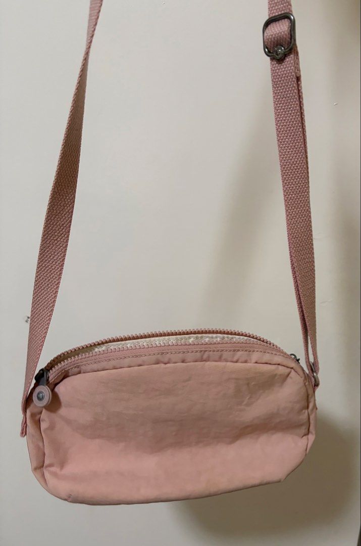 Kipling Pink Nylon Crossbody Bag (Category: Cross-body Bags) located in Angeles City. Submitted by chaegyoung (Listing ID 1470240779, Image 2). Description: - Authentic Kipling crossbody bag in a charming light pink shade - Durable nylon material with an adjustable shoulder strap for comfort - Secure zipper top closure opening to a spacious lined interior - Signature round Kipling logo patch on the front - Flaw note: Some dirt marks and stains ar