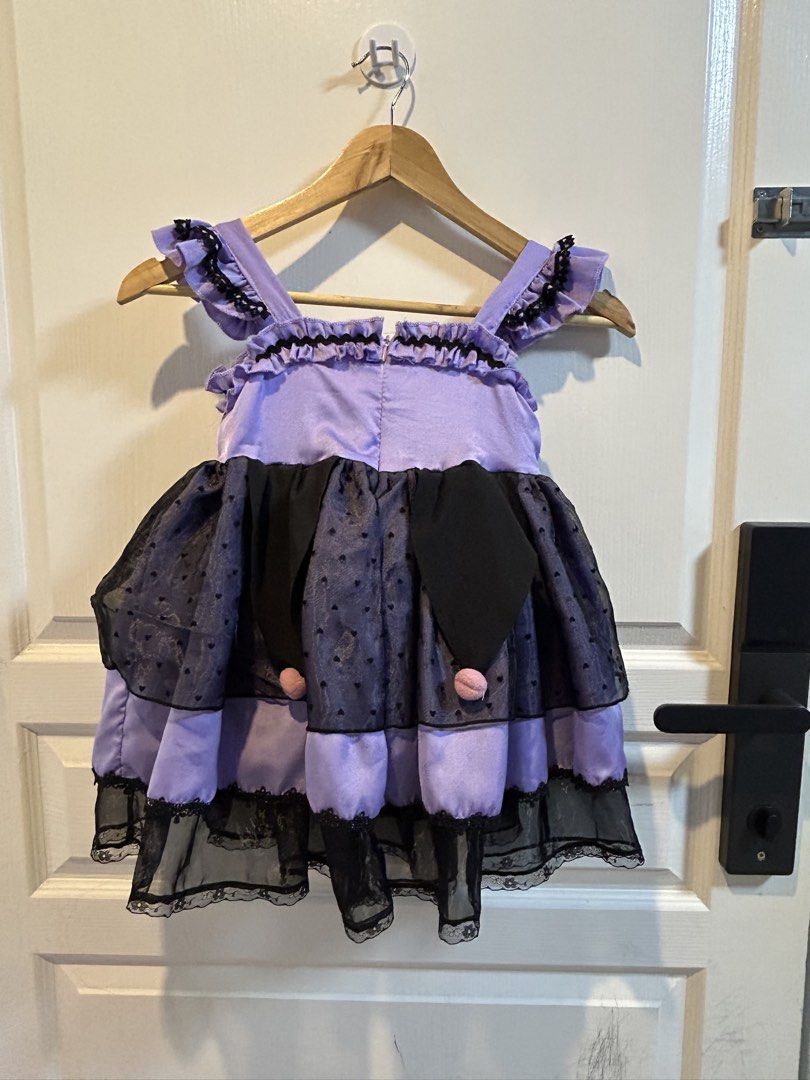 Kuromi Costume (Category: Babies & Kids Fashion) located in Dasmarinas. Submitted by princesisla (Listing ID 1470159437, Image 2). Description: - Style: Gothic lolita children's dress in purple and black - Details: Ruffled straps, delicate lace trim, and a polka dot sheer overlay - Back Design: Convenient zipper closure with a large decorative bow and ribbon lacing - Accents: Two playful dangling pom-poms on the skirt - Perfect For: Costume parti