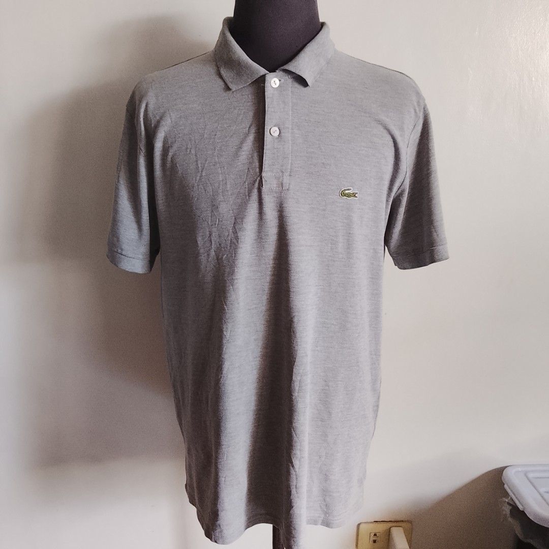 Lacoste - Gray Polo Shirt (Category: Luxury Apparel) located in Angeles City. Submitted by sselects_ (Listing ID 1470157272, Image 1). Description: Details of the item: *Color may vary due to lighting Size: 6 on tag, fits L-XL imo Width: 21" Length: 28" Issue: small yellow stain on button part, removable Condition: Good ALL ITEMS ARE NEGOTIABLE.