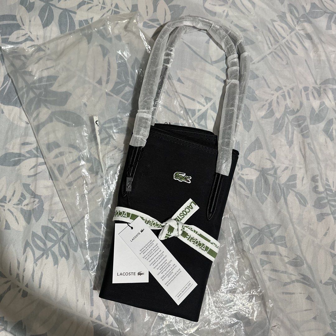 Lacoste Black Tote Bag with Ribbon and Tags (Category: Tote Bags) located in Marikina City. Submitted by bry_lei26 (Listing ID 1470293721, Image 3). Description: - Color: Classic black with iconic crocodile logo on the front - Secure zipper closure with branded pull tab - Double top handles (still wrapped in protective plastic) - Interior zipped pocket with debossed logo patch - Includes a stylish green and white decorative ribbon - Comes with a 