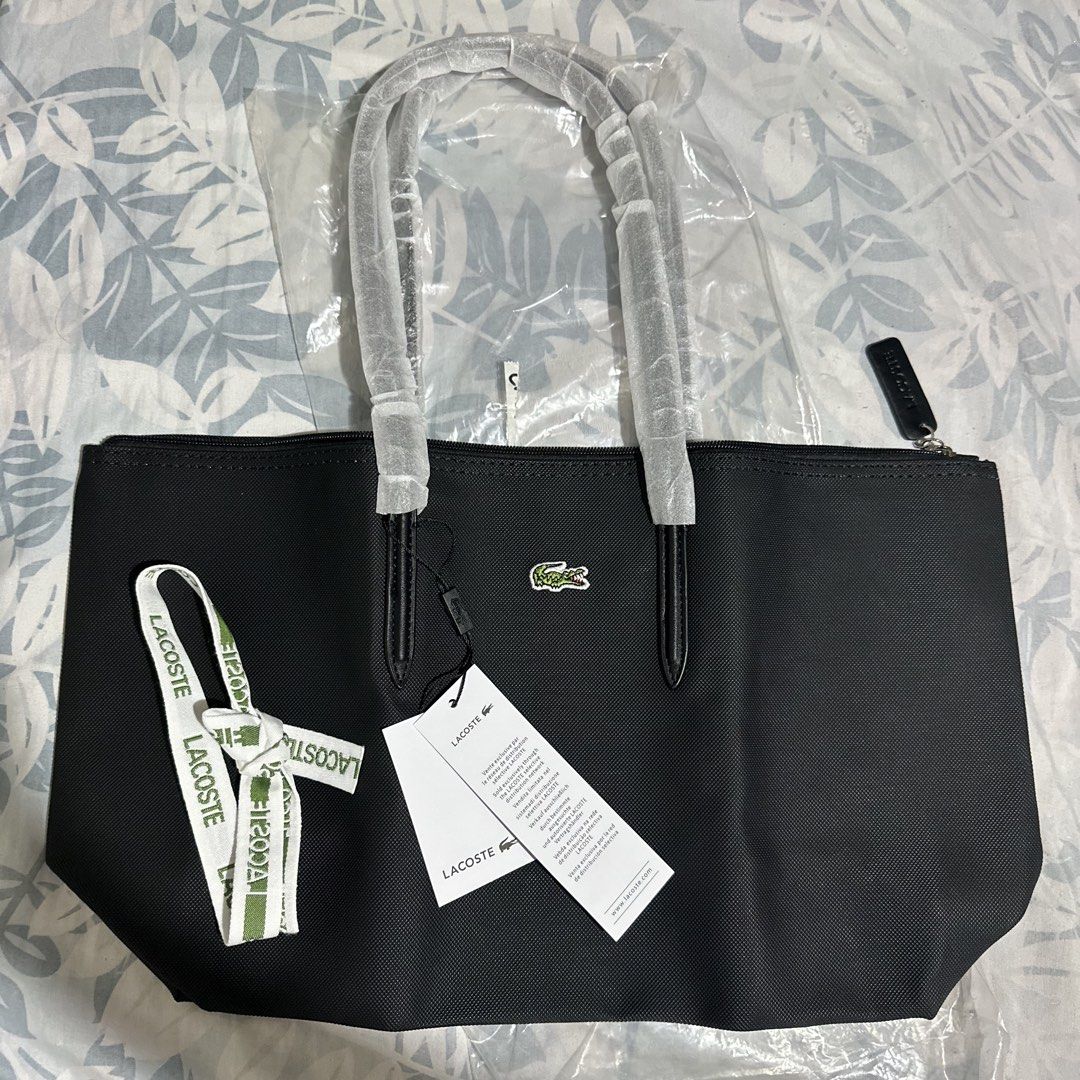 Lacoste Black Tote Bag with Ribbon and Tags (Category: Tote Bags) located in Marikina City. Submitted by bry_lei26 (Listing ID 1470293721, Image 1). Description: - Color: Classic black with iconic crocodile logo on the front - Secure zipper closure with branded pull tab - Double top handles (still wrapped in protective plastic) - Interior zipped pocket with debossed logo patch - Includes a stylish green and white decorative ribbon - Comes with a 