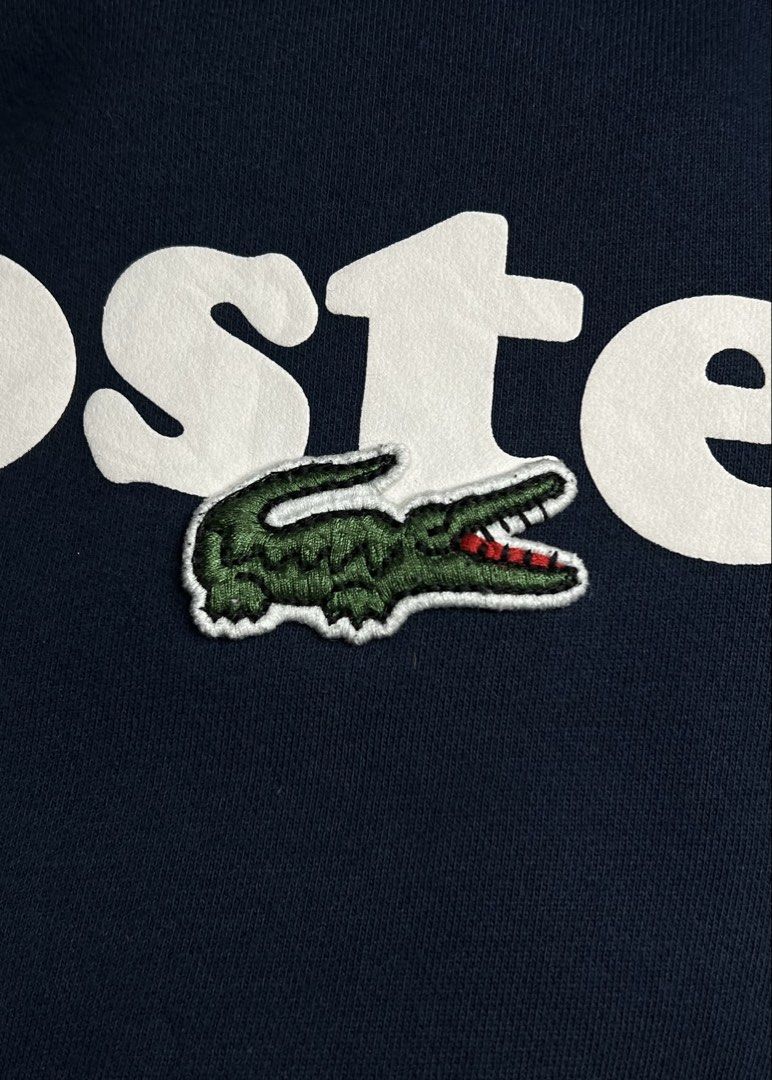Lacoste Classic Fit Navy Blue Sweatshirt (Category: Coats, Jackets and Outerwear) located in Luna. Submitted by lareign (Listing ID 1470290728, Image 3). Description: - Color: Navy Blue - Design: Big white script logo across the chest with the iconic semi big embroidered logo - Size: US XL / FR 6 (Measures 22" x 27") -Color rate: 9.5/10 -Honest Issue: minimal bacon on neckline and very small crack on print (Shown in the last slides) - overall: st