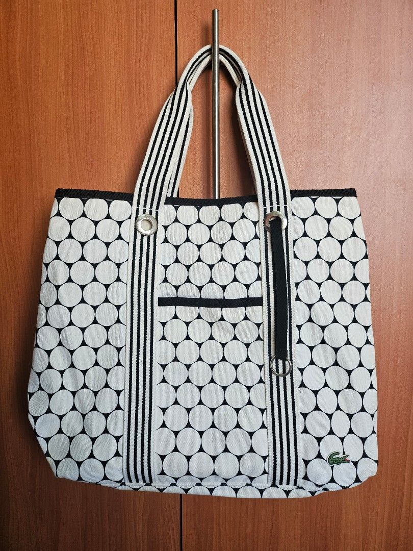 Lacoste Golf Ball Design Beach Bag (Category: Tote Bags) located in Mandaluyong City. Submitted by ohwmaria (Listing ID 1470232205, Image 2). Description: - Authentic Lacoste canvas tote bag in a chic black and white polka dot print - Sturdy striped webbing handles accented with silver-tone grommets and rings - Convenient exterior slip pocket on the front for quick-access items - Classic embroidered green crocodile logo patch near the top corner 