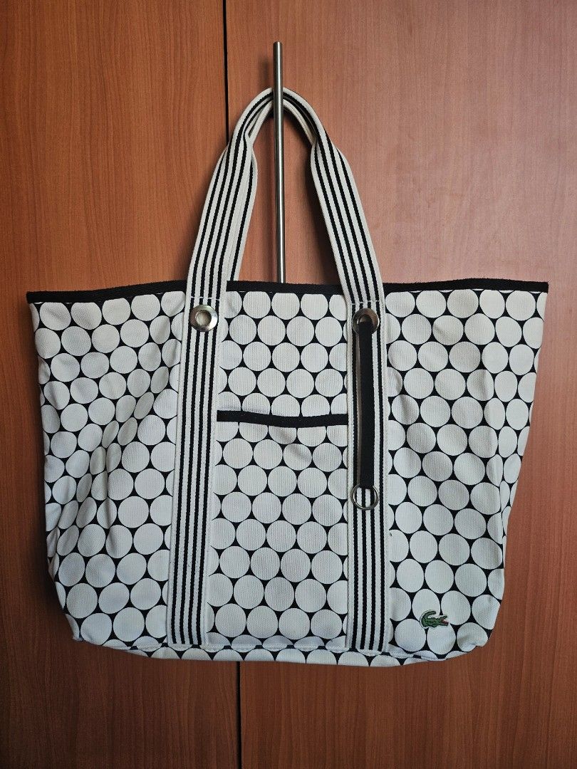 Lacoste Golf Ball Design Beach Bag (Category: Tote Bags) located in Mandaluyong City. Submitted by ohwmaria (Listing ID 1470232205, Image 1). Description: - Authentic Lacoste canvas tote bag in a chic black and white polka dot print - Sturdy striped webbing handles accented with silver-tone grommets and rings - Convenient exterior slip pocket on the front for quick-access items - Classic embroidered green crocodile logo patch near the top corner 
